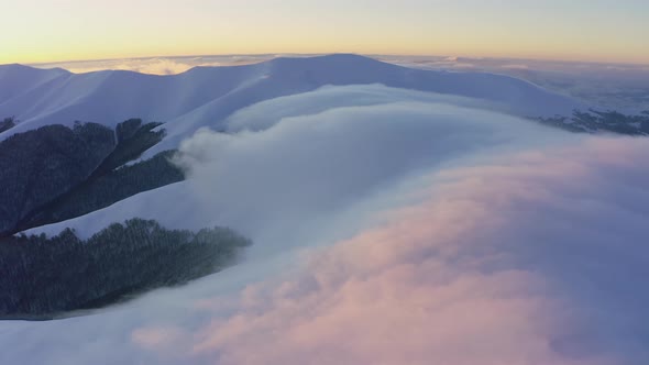 Cloud Waves Gently and Slowly Flow Over the Tops of Snowcapped Mountains Covered with Spruce Forests alt