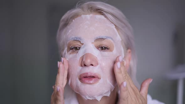 Headshot Confident Middle Aged Caucasian Woman Applying Face Mask in the Morning at Home Looking at alt