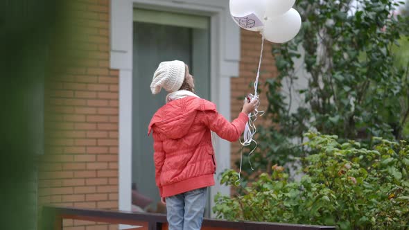 Back View Teenage Caucasian Girl on Autumn Spring Day Outdoors with White Balloons alt