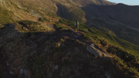 Aerial View of Hiker Man with Backpack on Top of a Mountain alt