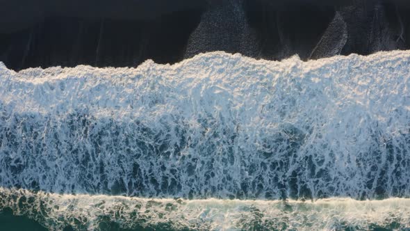 Aerial view of ocean wave splashes into the sand coast alt