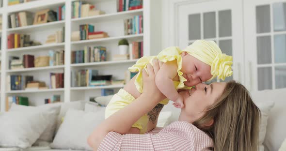 Young Beautiful Mom Blonde Holding a Newborn Baby in Her Arms Indoors