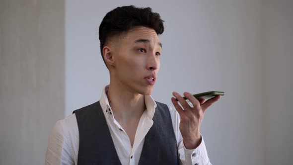 Young Asian Businessman Talks to Employee on Mobile Phone alt