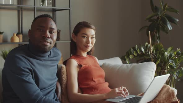 Portrait of Multiethnic Family Couple Sitting on Sofa with Laptop alt