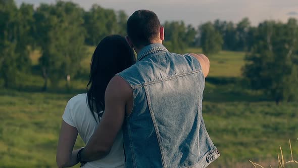 Close Backside View Young Couple Stands Against Green Trees alt