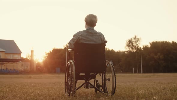 Disabled Person Woman is Sitting Wheelchair in Middle of Field Background Sunset and Waving Her alt