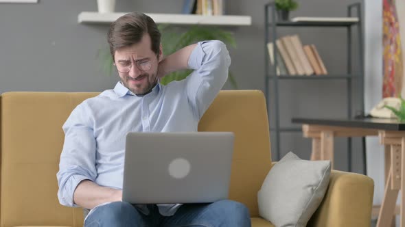 Young Man with Laptop Having Neck Pain on Sofa alt