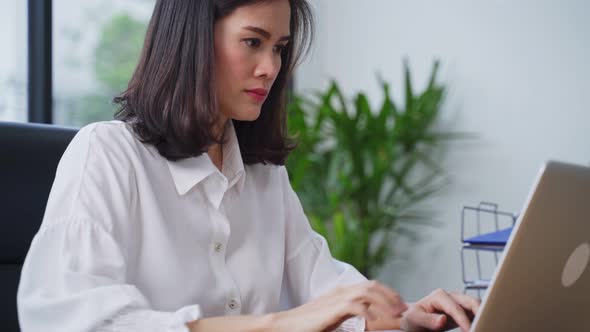 Asian young business woman sit on table work on a computer in the office with a new normal lifestyle alt