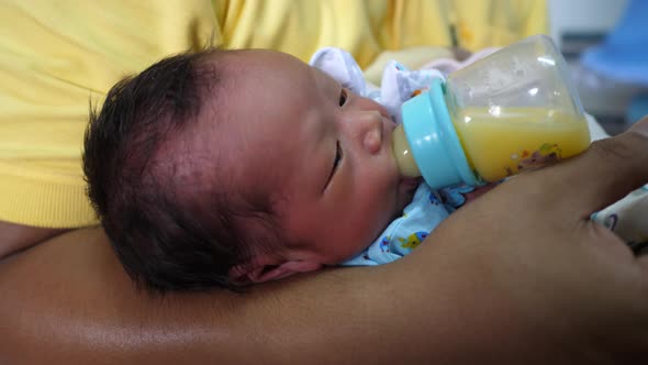 The newborn is eating breast milk from a bottle, slow-motion shot alt