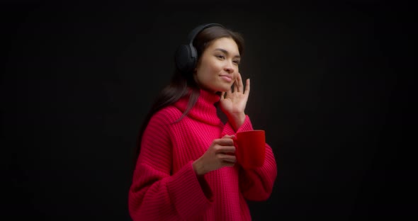 Beautiful Woman in a Bright Pink Sweater Enjoys Music in Wireless Headphones