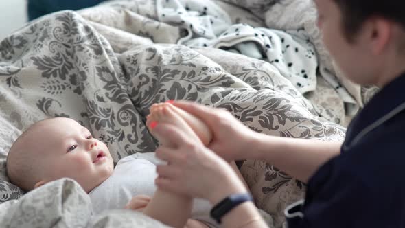 Mother Plays with Her Baby at Home on Her Lap