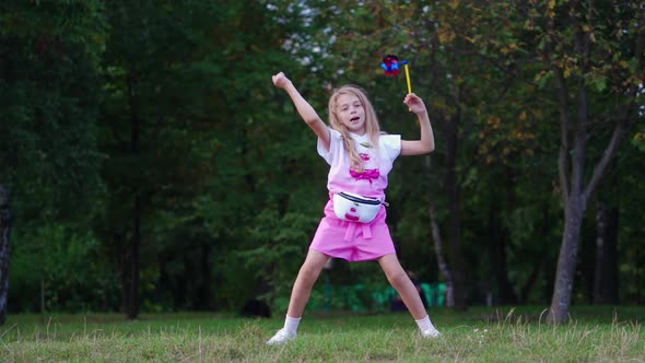 Little girl with colorful pinwheel in park. alt