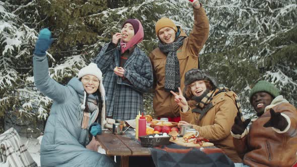 Portrait of Happy Friends at Camp Table in Winter Forest alt