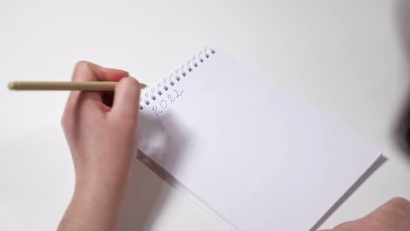 Unrecognizable Lefthanded Woman Writes Goals for 2022 on Paper alt