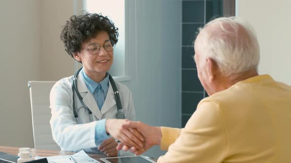 Doctor and patient shaking hands and kindly talking