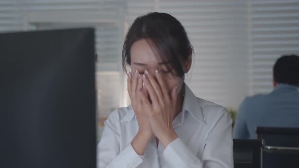 Tired Asian Female Worker Working on desktop computer in the Corporate Office,
