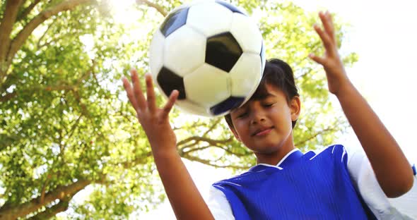 Smiling boy playing a football in park alt
