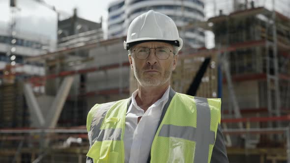 Portrait of Builder in Helmet Posing on Construction Site alt