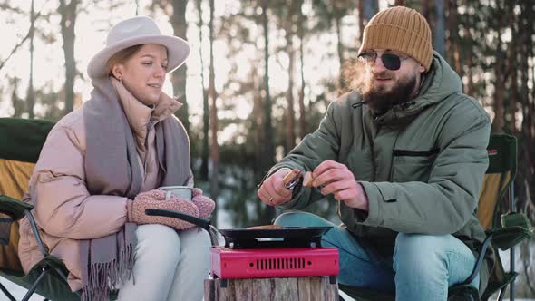 Couple Cooking Lunch at the Camp on a Portable Stove in the Woods on a Sunny Day
