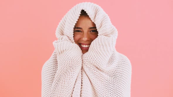 Young Female in Sweater is Feeling Cold Wrapping Herself Up with a Blanket and Laughing While Posing alt
