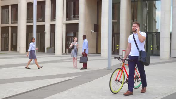 Friendly Businessman with Bicycle Speak on Phone Downtown alt