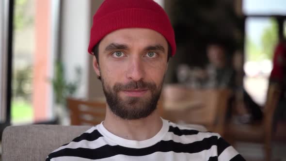 Handsome guy with a beard looks at the camera, then looks away. alt