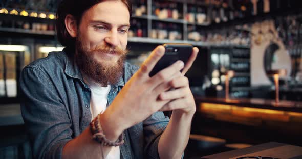 Bearded Male with Smartphone in Cafe