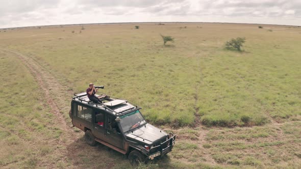 Photographer photographing from roof of vehicle while on african wildlife safari in Kenya. Aerial dr alt