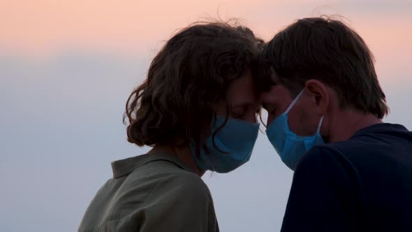 Couple in Protective Masks. Side View Close Up Faces of Man and Woman in Medical Mask Touches