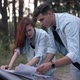 Positive Couple Talking Gesturing Examining Paper Map on Car Hood in Forest - VideoHive Item for Sale
