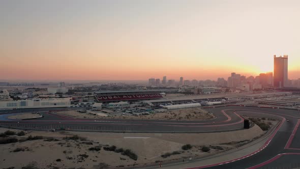 Aerial view of Dubai Autodrome race track and paddock, Dubai skyline at sunset