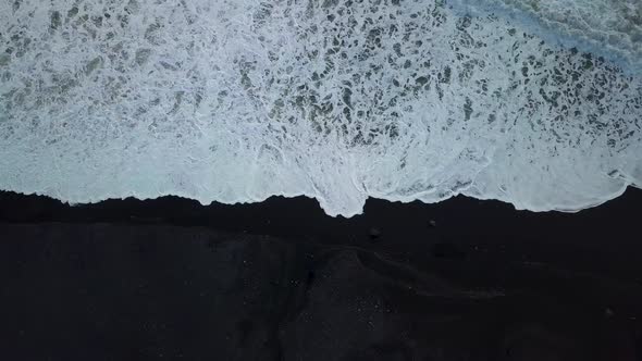 Waves coming up onto the black sand beach near Vik in Iceland from drone alt