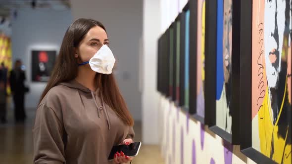 Young Woman in Respirator Mask Considers Exhibitions in Museum. Female Tourist at Exhibition in