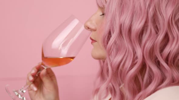 Beautiful Relaxed Young with Pink Curly Hair Drinking Rose Wine Hold Wine Glass Over Bright Pink