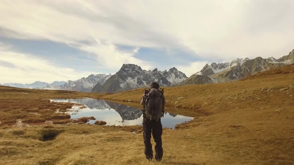 Man Photographer Hiker Shoot Photo Near Lake to Snowy Mounts