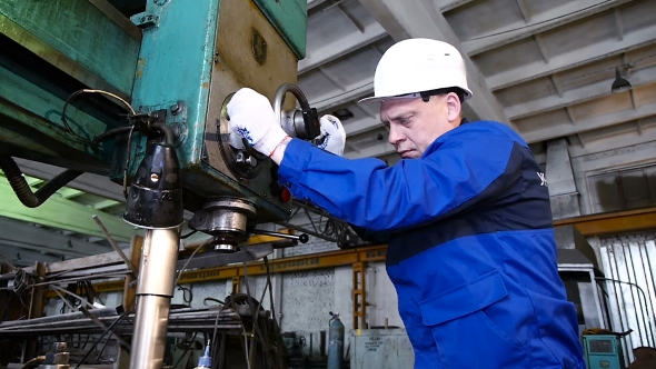 Man Drilling With a Machine Making a Hole In a Steel Bar