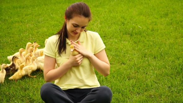 Footage Woman Holding a Little Duck In Hand And Sitting On Green Grass alt