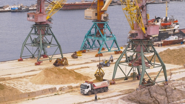 Industrial Port Area. Crane With Bucket Loads Mortar Sand in the Truck. alt