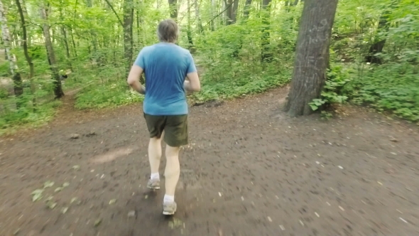 Adult Man Running Jogging Outdoors In a Forest Nature On a Forest Trail And Enjoying It