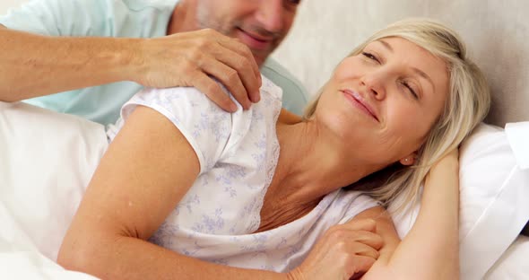 Couple relaxing in bed and smiling at camera alt