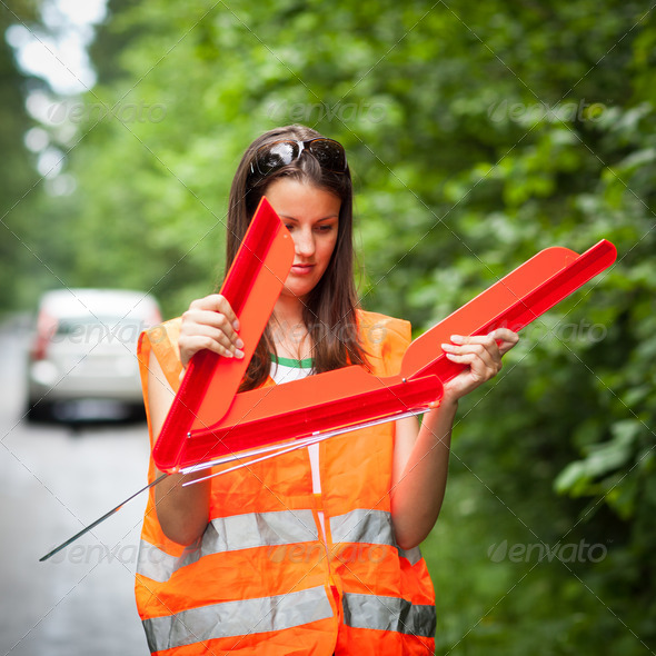 Young female driver wearing a high visibility vest, calling the - Stock Photo - Images