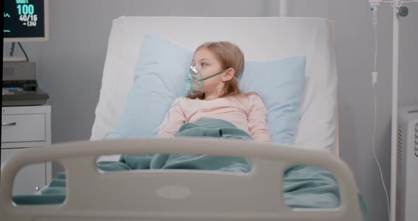 Girl Suffering From Pneumonia Lying in a Hospital Bed with Oxygen Mask alt