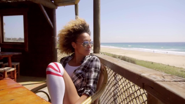 Young Woman Relaxing At a Beachfront Cafeteria alt