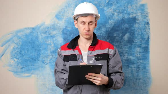 Concentrated Man Builder Makes Notes on Repair Plan in Room alt