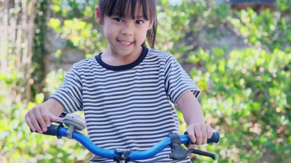 Cheerful smiling girl ringing a bicycle. alt