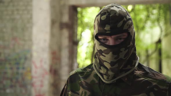 Portrait of Soldier in Camouflage Uniform Looks at Camera and Throws Off Cap alt