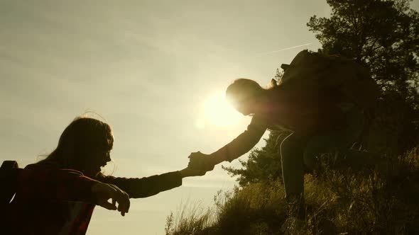 Women Travelers Climb the Mountain, Holding Out Their Hand, Helping To Climb. Teamwork Travelers alt