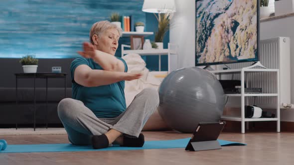 Elder Person Doing Physical Exercise and Watching Online Lesson alt