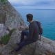 Young Hipster Guy Sitting On The Rock Mountains Near Sea, Man With a Rucksack On His Back - VideoHive Item for Sale