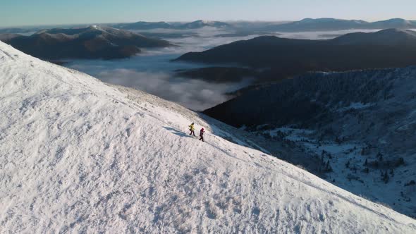 Two Mountaineers Descending a Mountain Ridge Covered in Snow